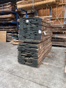 a stack of raw waney edge walnut timber on a pallet at the timber yard
